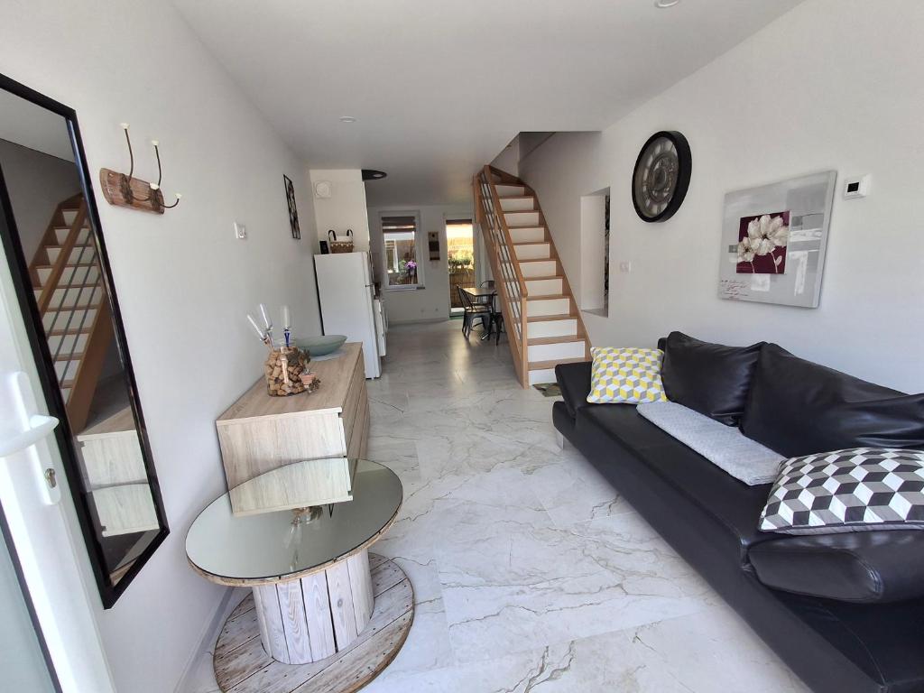 un salon avec un canapé noir et une table dans l'établissement Auxpetitsloups, à Issancourt-et-Rumel