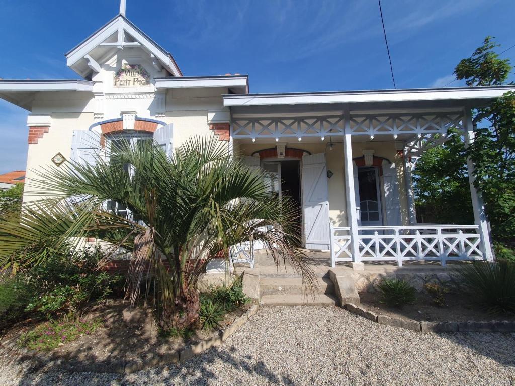 une maison blanche avec un palmier devant dans l'établissement Villa soulacaise - 3482, à Soulac-sur-Mer