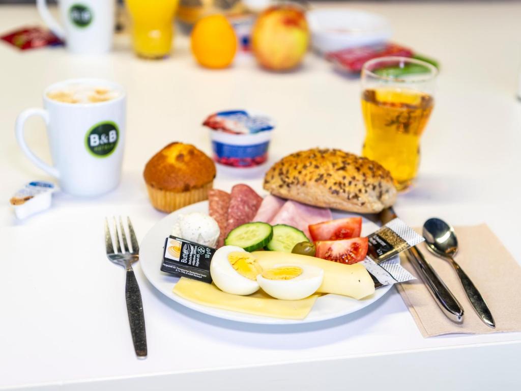 a plate of food with eggs and fruit on a table at B&B HOTEL Dortmund-Airport in Holzwickede