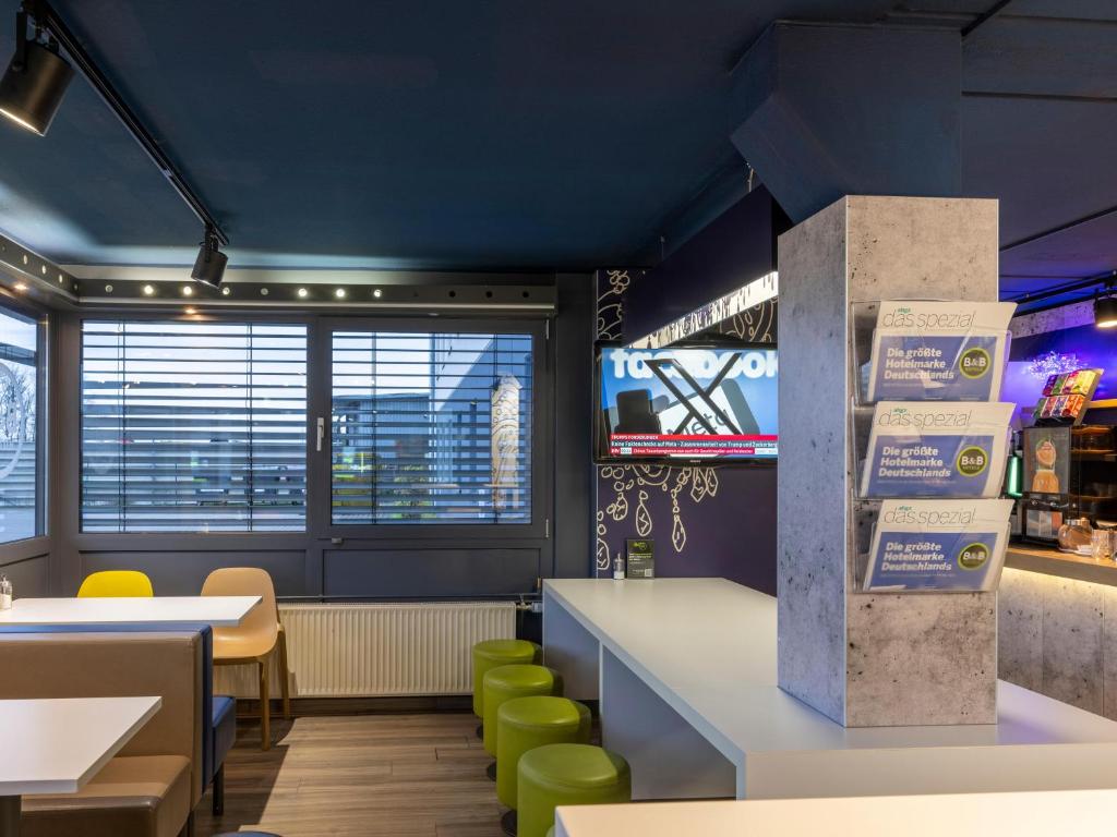 a fast food restaurant with tables and green chairs at B&B HOTEL Dortmund-Airport in Holzwickede