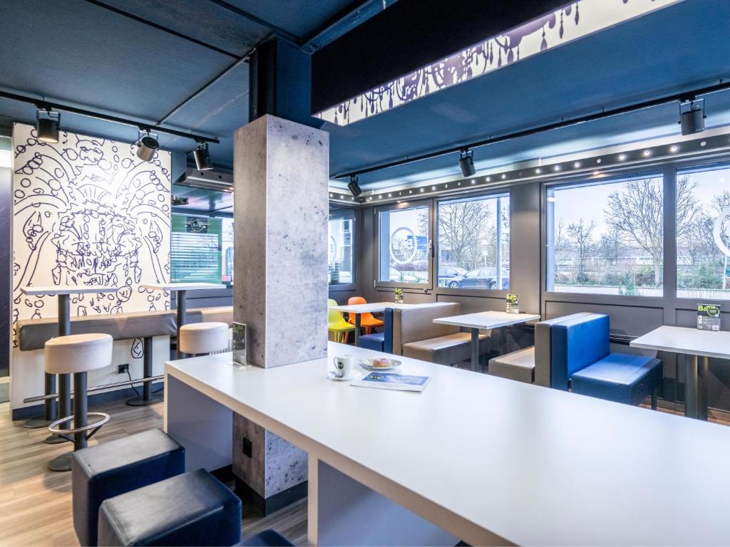 a restaurant with a large white counter and chairs at B&B HOTEL Dortmund-Airport in Holzwickede