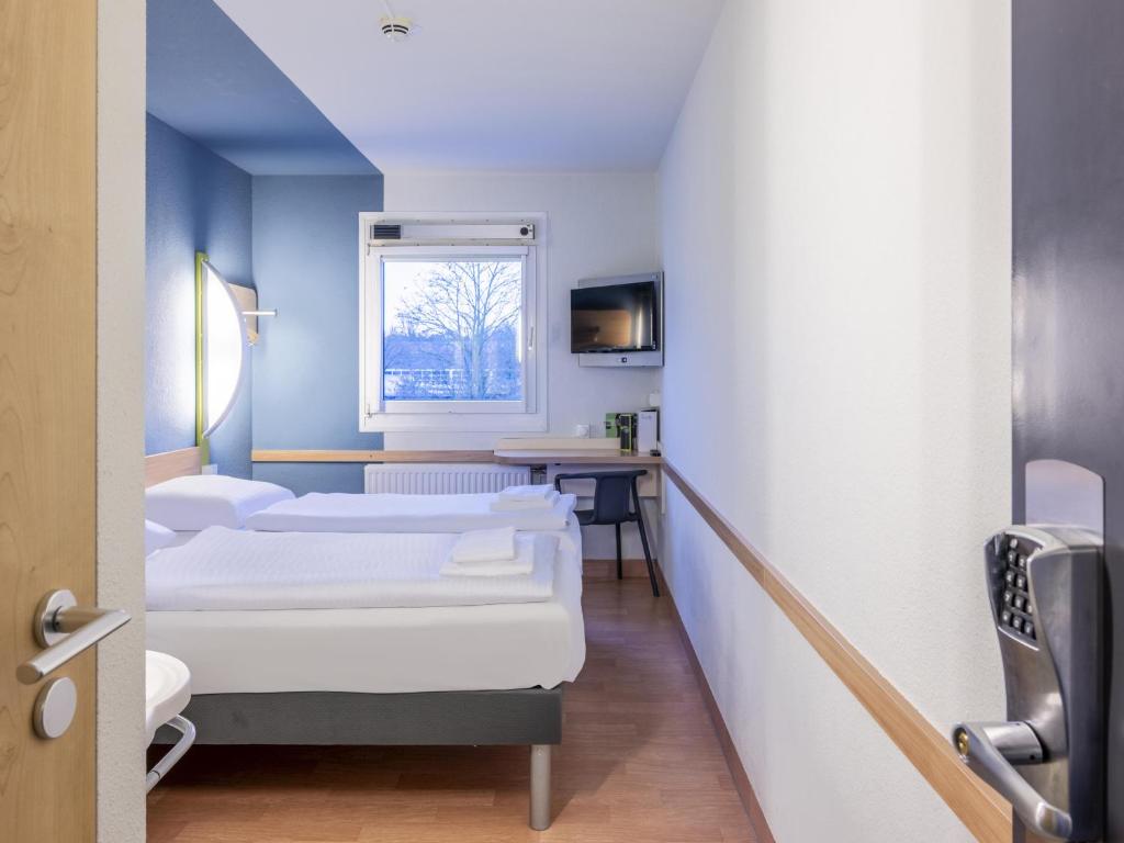 a hospital room with three beds and a window at B&B HOTEL Dortmund-Airport in Holzwickede
