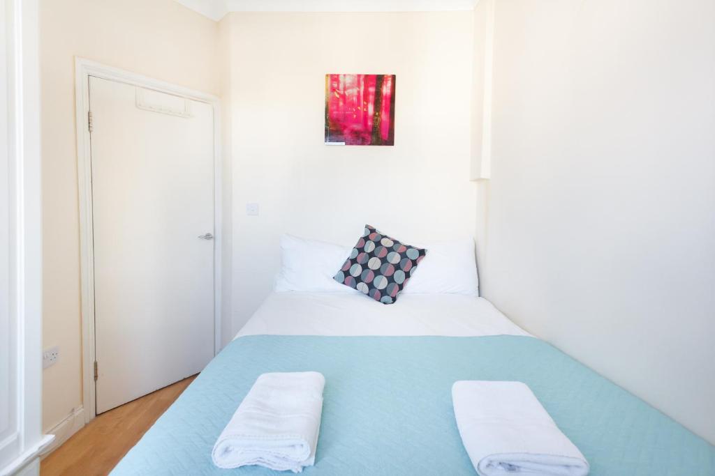ロンドンにあるEuston Budget Apartments and Roomsの小さなベッドルーム(青と白のベッド付)