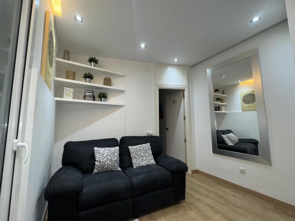 a living room with a black couch and a mirror at Apartamento con patio en Madrid centro in Madrid