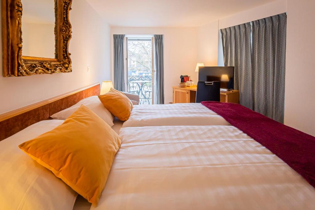 a bedroom with a large white bed with yellow pillows at Hôtel du Cheval Blanc - City center in Bulle