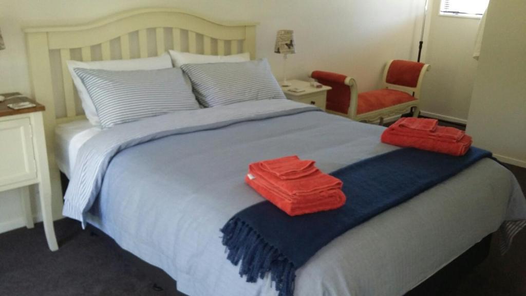 a bedroom with a bed with two red towels on it at Jan's Boutique B & B Suite in Christchurch
