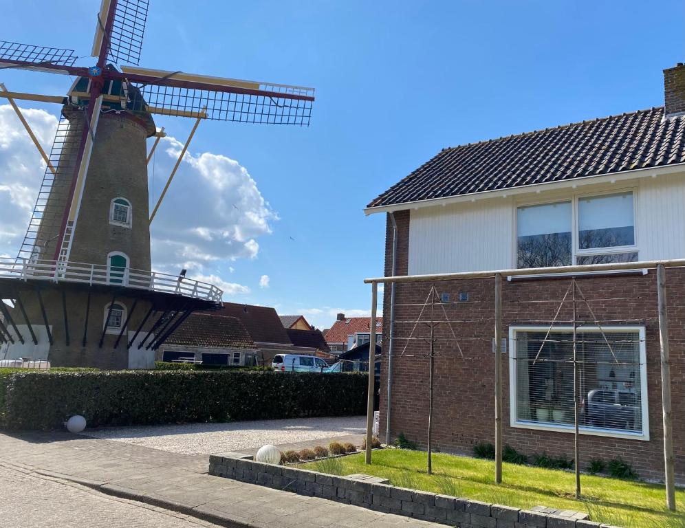 a house and a windmill in front of a house at Spacious house next to the mill! in Westkapelle