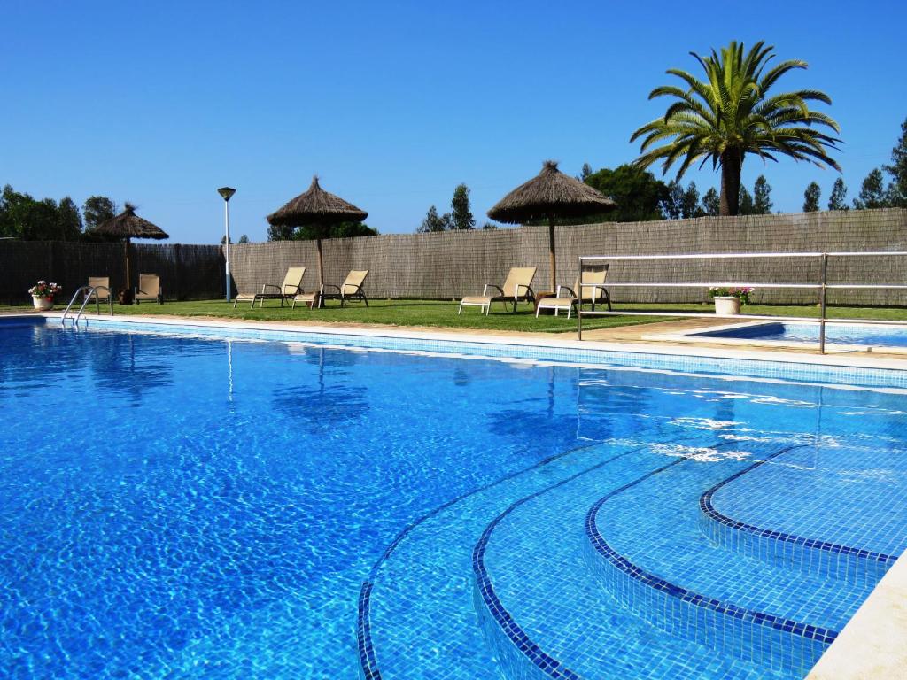 a large blue swimming pool with chairs and umbrellas at Herdade Moita Mar - Country & Sea in Vila Nova de Milfontes
