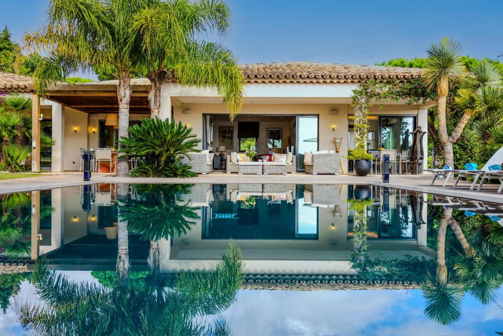 une maison avec une piscine et des palmiers dans l'établissement Villa Les Rostratas, à La Croix-Valmer