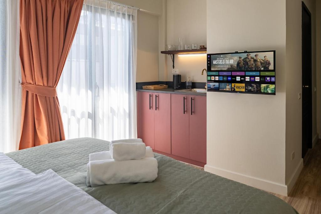 a bedroom with a bed with a white chair and a tv at Boutique hotel Axis Bangkok in Bangkok