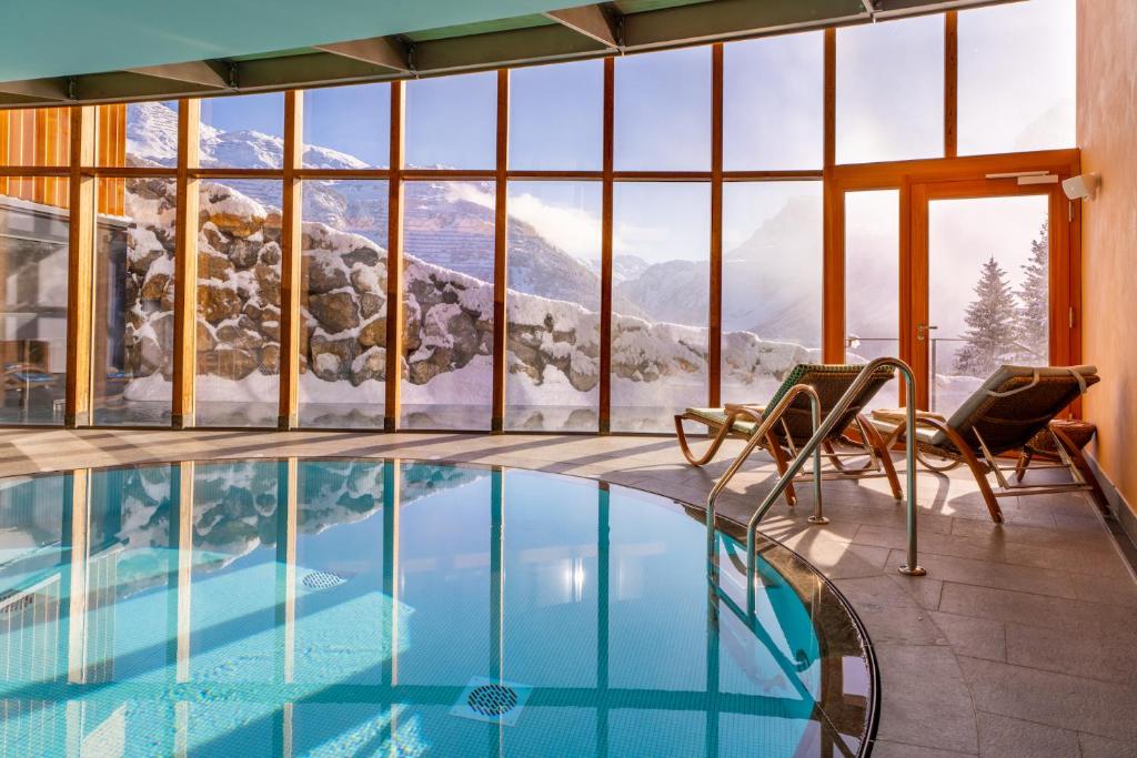 a pool with a view of a snowy mountain at Hotel Goldener Berg in Lech am Arlberg