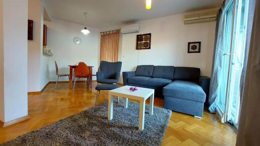 a living room with a blue couch and a table at Sea & Mountain View Apartment in Budva