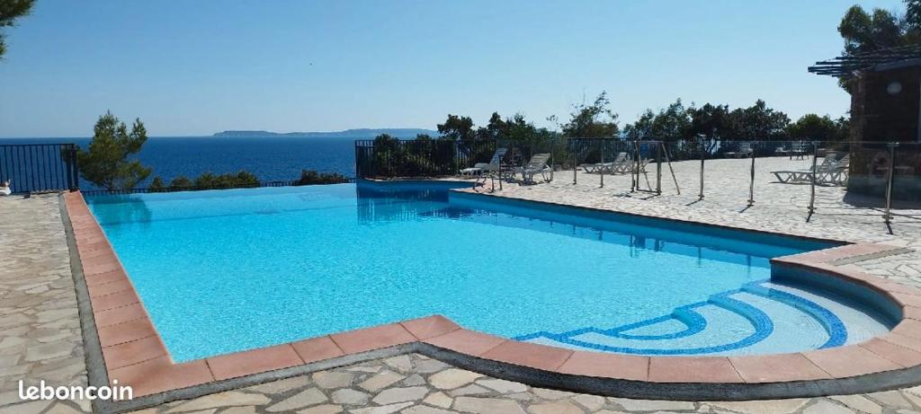 une grande piscine avec de l'eau bleue dans l'établissement T2, Piscine en saison, Terrasse, Plage, parc privé, au Lavandou