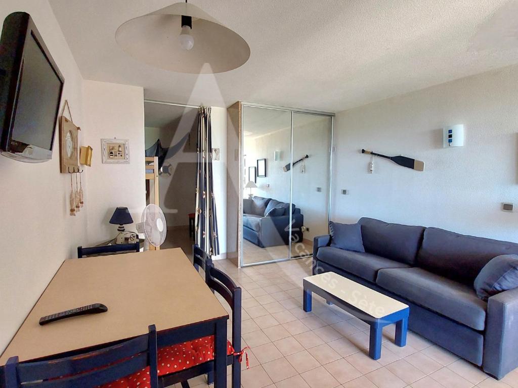 un salon avec un canapé et une table dans l'établissement Studio cabine en rez de jardin dans residence avec piscine, à Sète