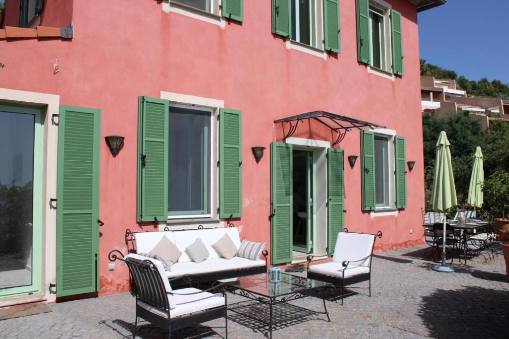un bâtiment rose et vert avec des chaises et une table dans l'établissement La bastide, à Vallauris
