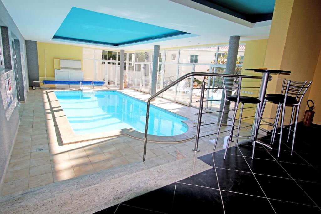 a swimming pool with chairs and a blue umbrella at Apartments Villa Ceres in Klek