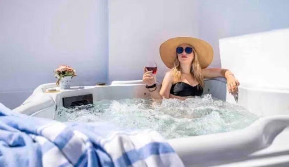 a woman in a bathtub holding a glass of wine at Luxury Vacation Villa Irene with private juccuzi in Fira