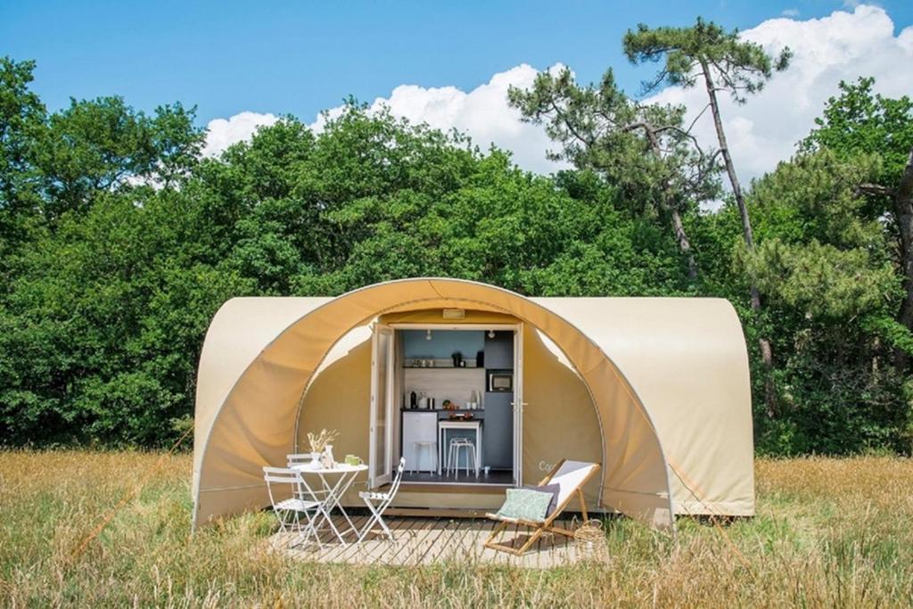 a tent with a table and chairs in a field at AIRE NATURELLE CAMPING LA LOIRE FLEURIE in Le Perrier