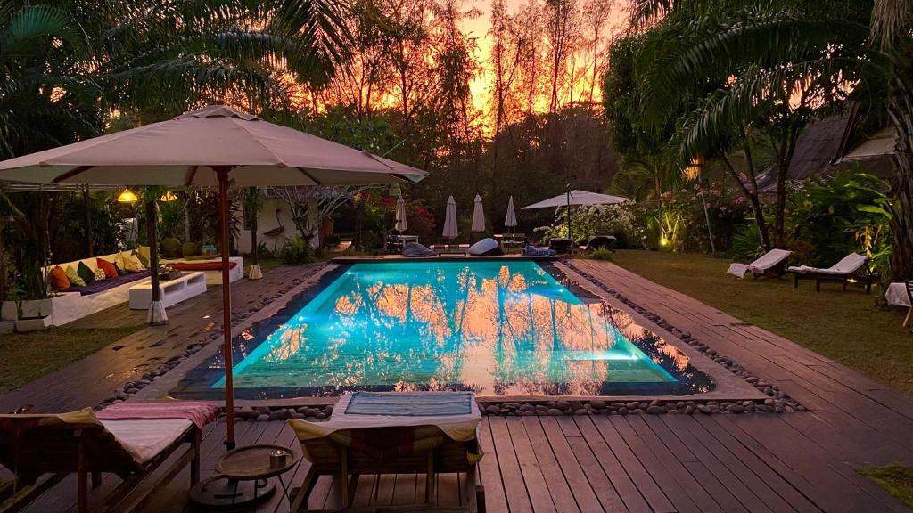 a swimming pool with an umbrella and tables and chairs at Maddekehaoo Eco Mansion in Ko Chang