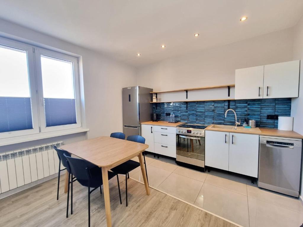 ラドムにあるMieszkanie z dostępem na kodの木製のテーブルとテーブルと椅子のあるキッチン