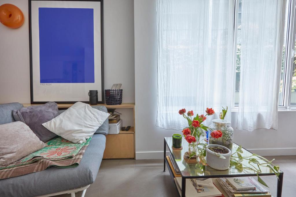 - un salon avec un canapé et une table fleurie dans l'établissement Chez Julie - République, à Paris