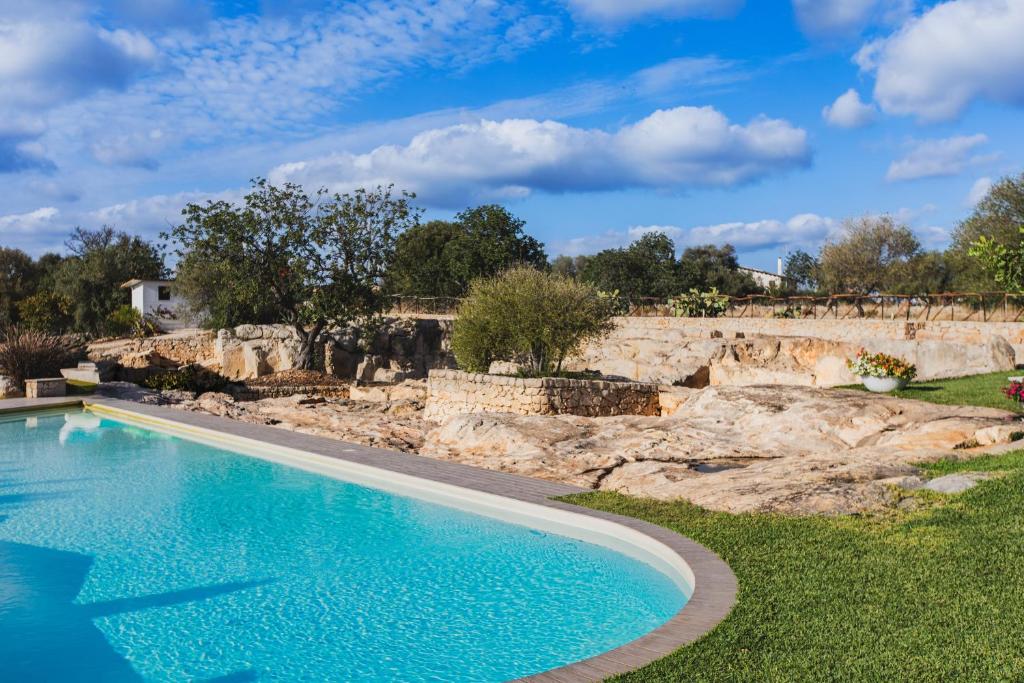 a swimming pool in a yard with a stone wall at Le Cave di Fontane Bianche in Cassibile