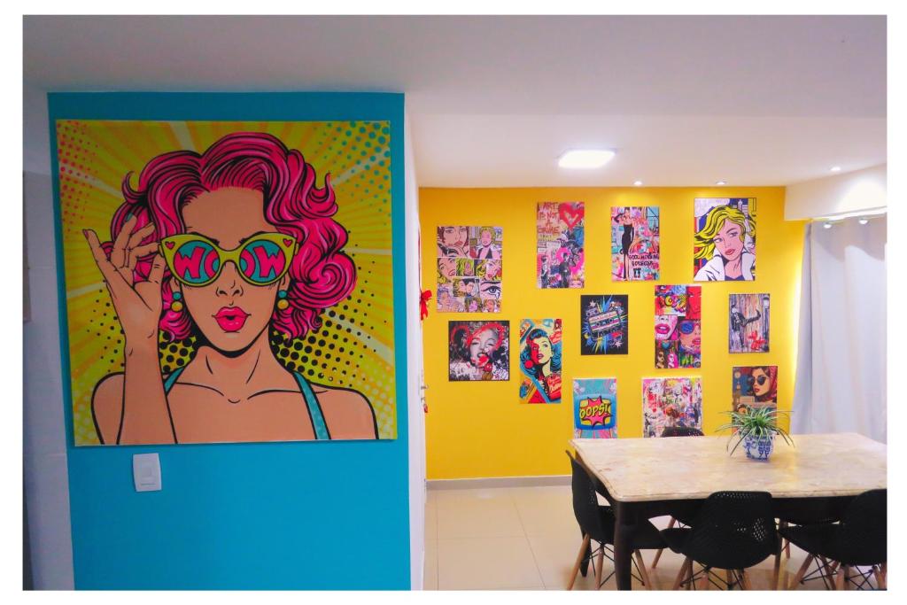 a dining room with a table and a painting of a woman with sunglasses at Apartamentos com 2 quartos na Praia de Itapema bairro Meia Praia in Itapema