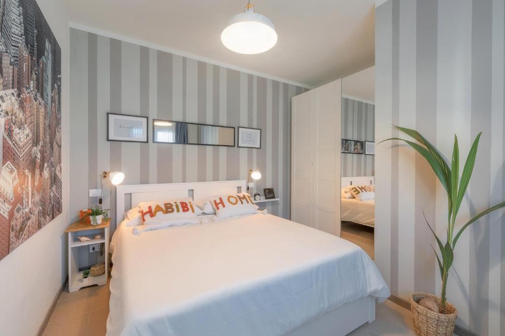 Un dormitorio con una cama blanca y una planta en maceta. en Casa Primavera, en Viareggio