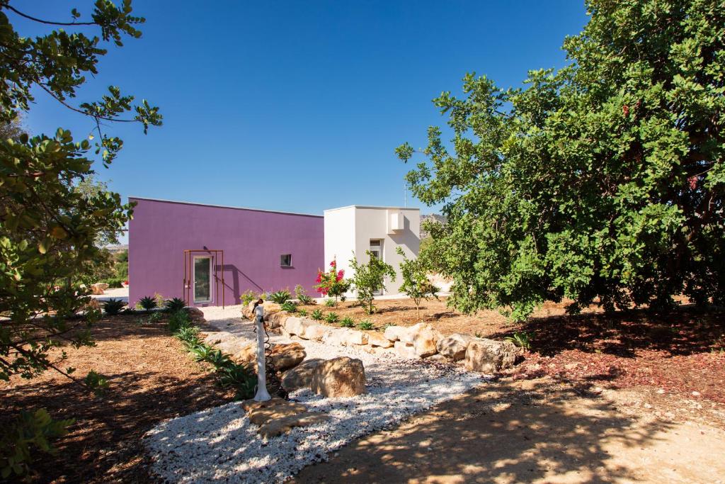 a purple house with a tree and a building at Le Cave di Fontane Bianche in Cassibile