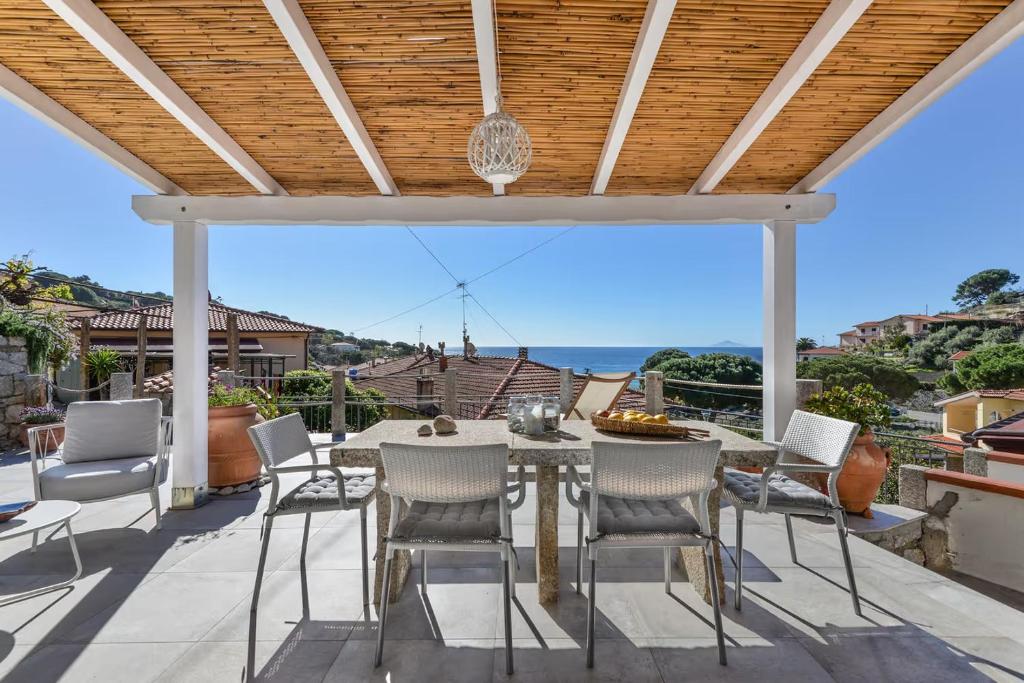 a patio with a table and chairs and a view of the ocean at Casa Melete - Goelba in Seccheto