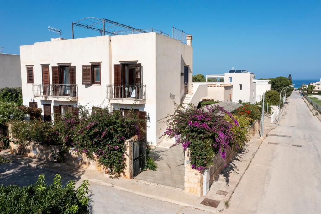 a white building with flowers on the side of a street at Casa Vacanza Azzurra in San Vito lo Capo