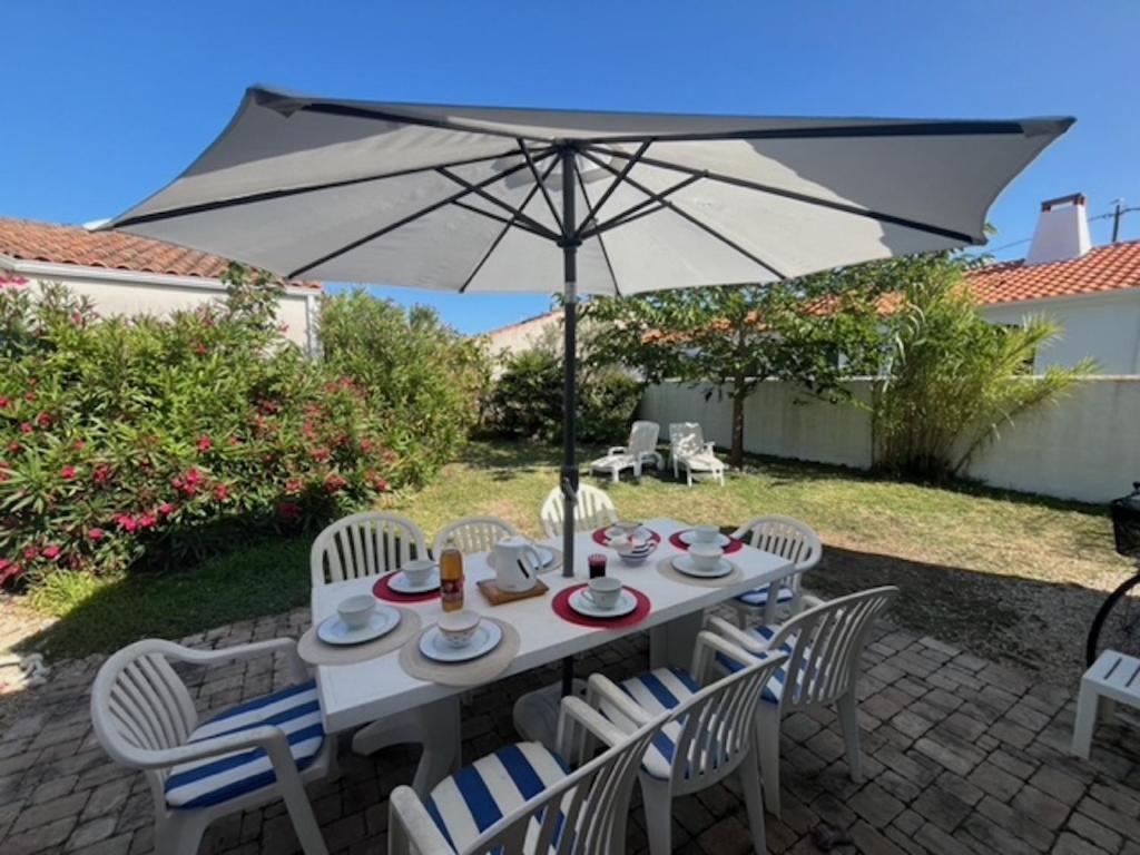 une table blanche avec des chaises et un parasol dans l'établissement Un sejour a huit dans cette grande maison a Saint Gilles Croix de Vie, à Saint-Gilles-Croix-de-Vie