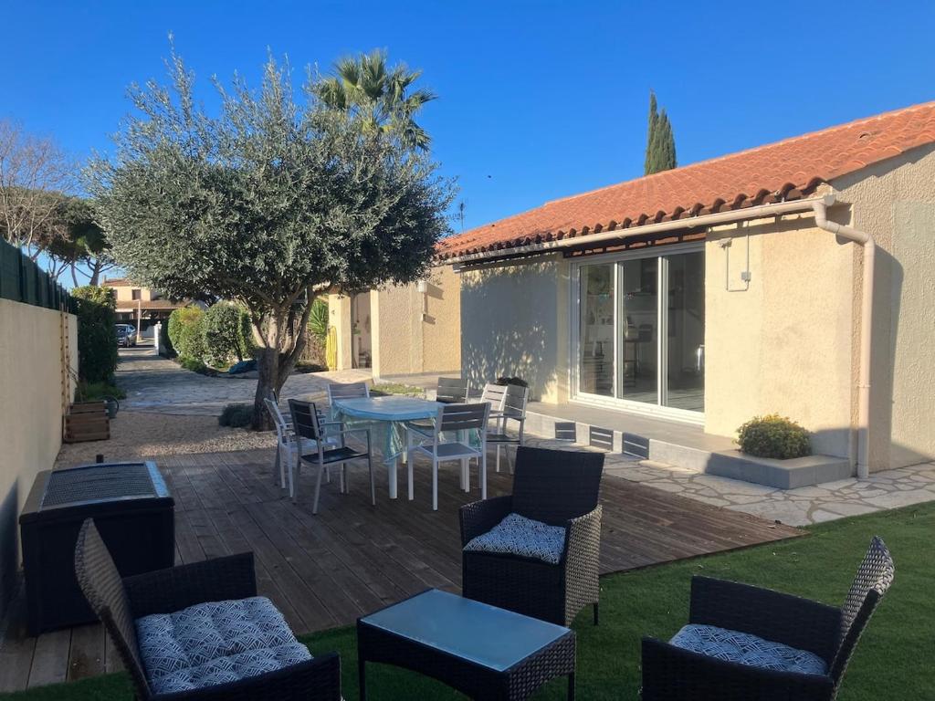 d'une terrasse avec une table, des chaises et un arbre. dans l'établissement Villa plain-pied tout confort 3 chambres avec jardin proche des plages, à Vias