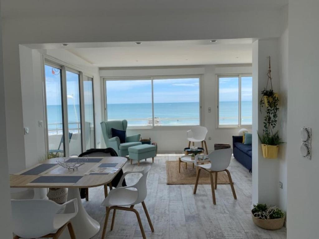un salon avec une table et des chaises et l'océan dans l'établissement Beau T3 180 degree sea view, à Palavas-les-Flots
