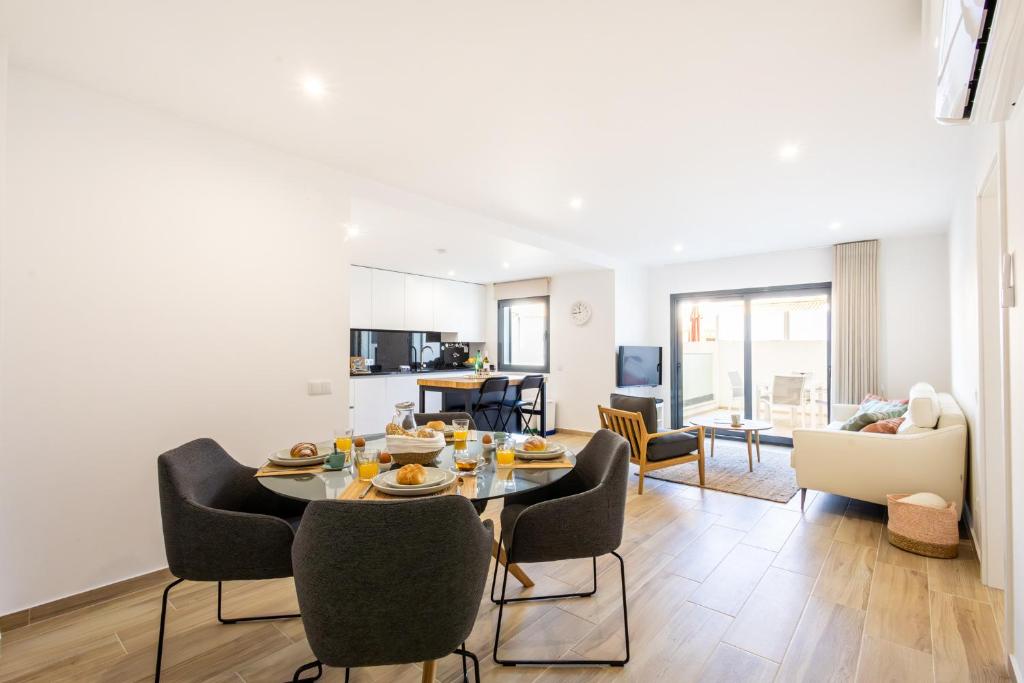 a dining room and living room with a table and chairs at Baia Mar T1 - By Smarthomes in São Martinho do Porto
