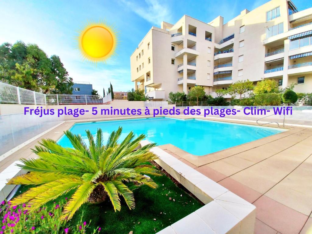 une piscine en face d'un bâtiment avec un palmier dans l'établissement 500m de la Mer- 4pers-Piscine-Parking-WiFi- Clim, à Fréjus