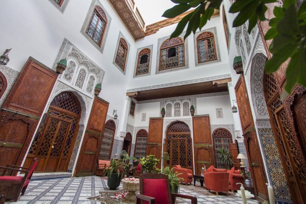 einen Innenhof einer Moschee mit roten Stühlen und Holztüren in der Unterkunft Riad - Dar Al Andalous in Fès