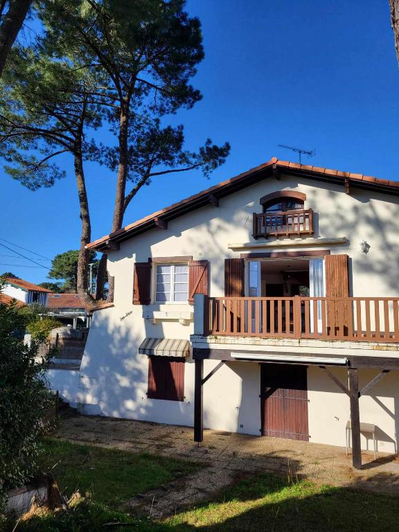 Cette maison blanche dispose d'une terrasse couverte et d'un balcon. dans l'établissement Appartement proche du lac d'Hossegor, à Soorts-Hossegor