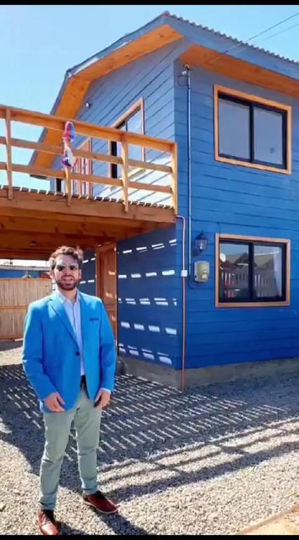 a man in a suit standing in front of a blue house at Casa Chagre los molles Brisas del mar in Los Molles