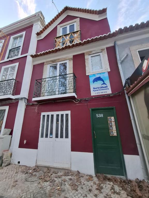 a red and white house with a green door at Setubal Apartments in Setúbal