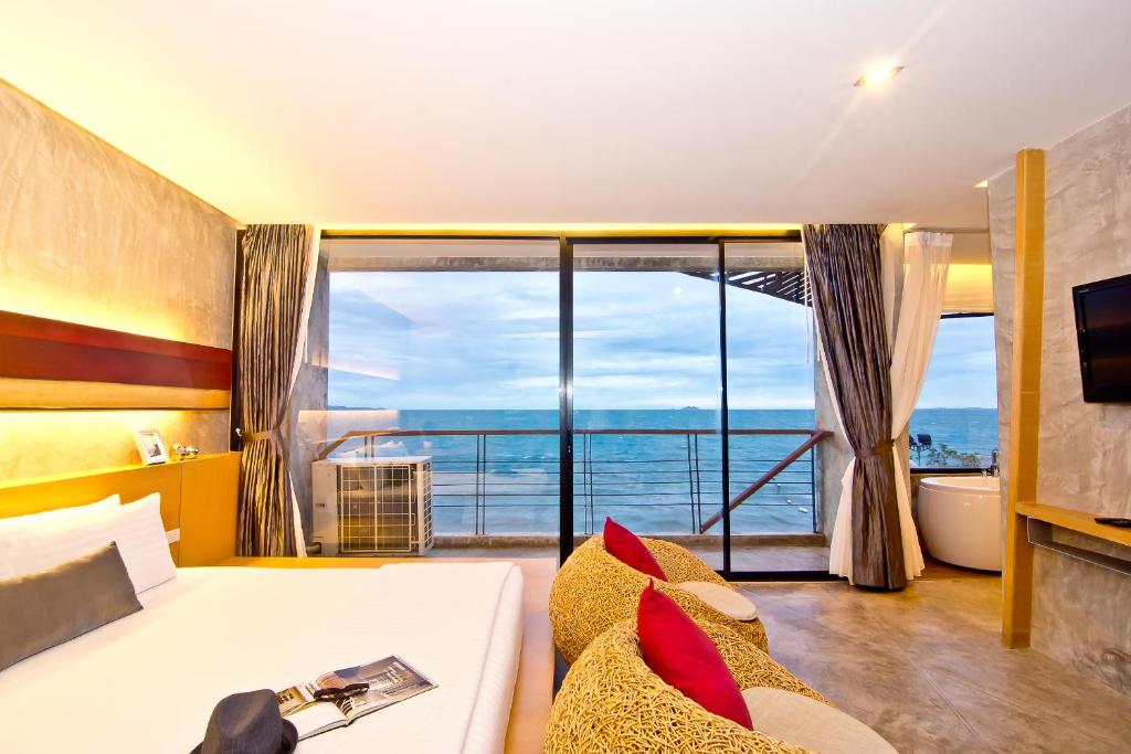 ジョムティエンビーチにあるThe Now Hotel - SHA Extra Plusのベッドと大きな窓が備わるホテルルームです。