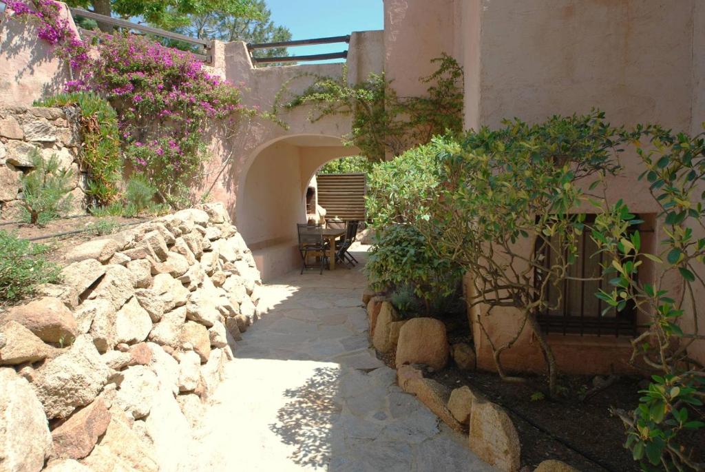 une passerelle en pierre menant à un bâtiment fleuri dans l'établissement Mini-villa à 5 minutes de la plage de Santa Giulia, à Porto-Vecchio
