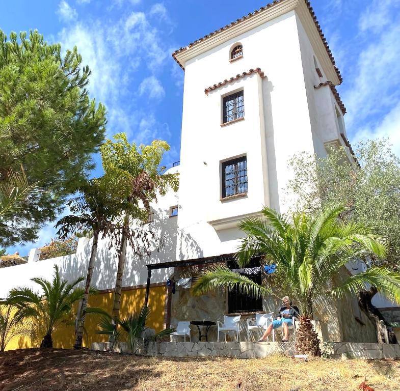 a person sitting in front of a building at Castle Tower apartment BERNARD in rural holiday park in Tolox