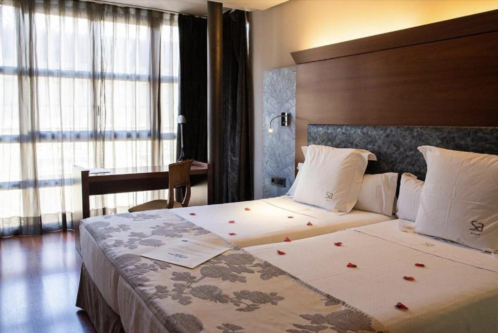 a bedroom with a large bed with red flowers on it at Hotel Sancho Abarca Petit SPA in Huesca