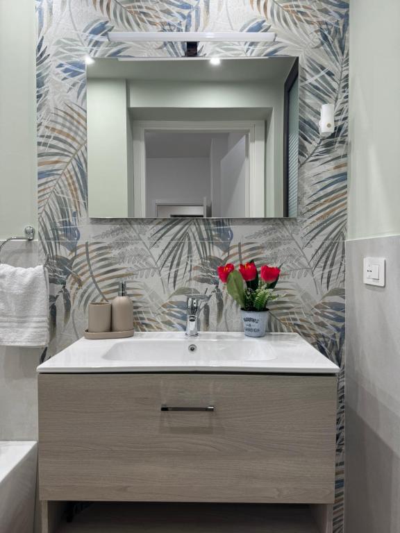 a bathroom with a sink and a mirror and red roses at Il Tulipano house in Catania