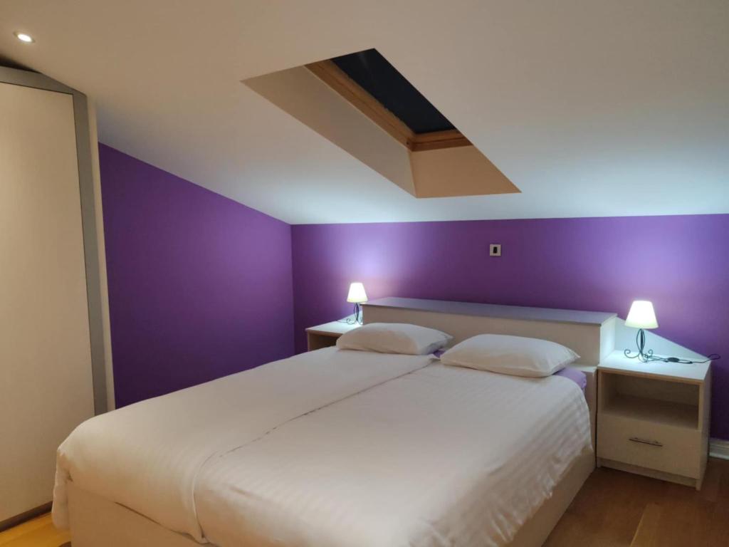 sypialnia z białym łóżkiem i fioletowymi ścianami w obiekcie Apartments Bosana XIV w Biogradzie na Moru