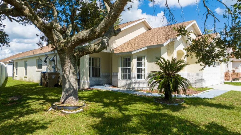 a white house with a tree in the yard at casa em orlando perto da disney com piscina house in area disney in Kissimmee