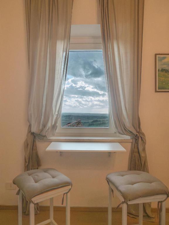 a window with a view of the ocean with two stools at dimora 13 in Casale Marittimo