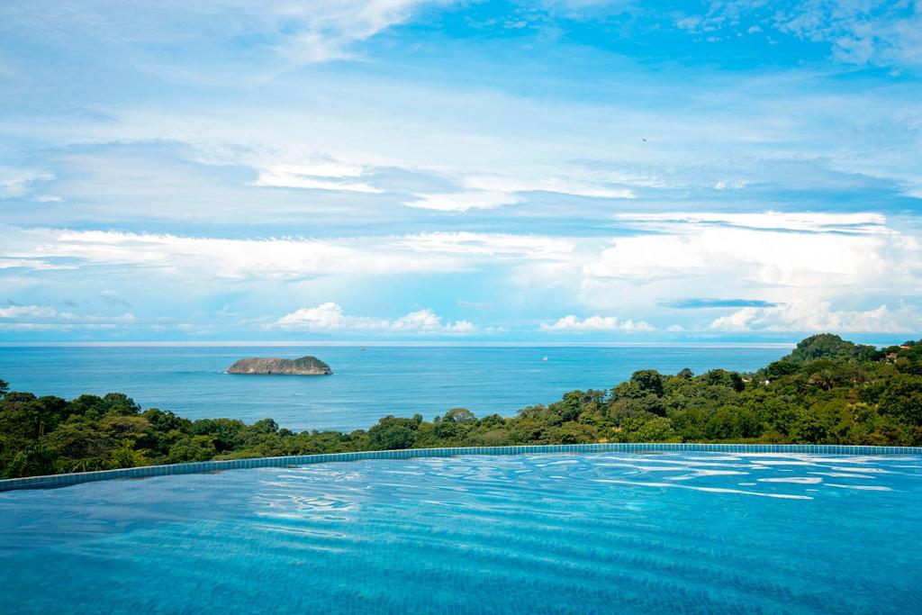 a swimming pool with a view of the ocean at Villa Roca Boutique Resort & Suites - ADULT ONLY in Manuel Antonio