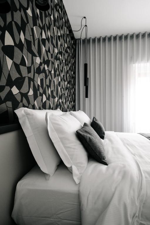 una camera da letto con un letto con lenzuola e cuscini bianchi di B&B LUMAS a Roma